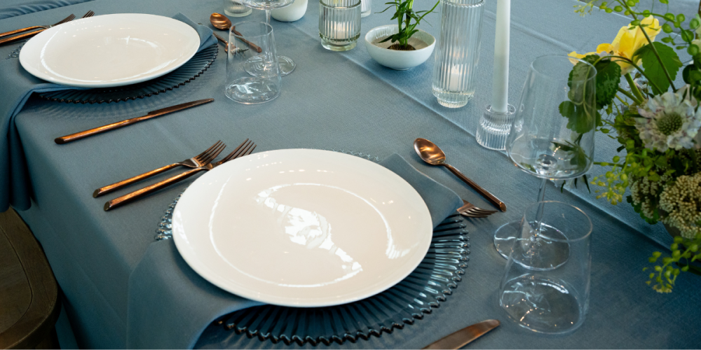 Blue linen corporate event tablescape at the Seattle Art Museum with white plates, copper flatware, and floral arrangements.